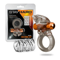 Stay Hard vibrating cock ring set by Blush featuring a vibrating ring with dual-prong stimulator attachment, bullet vibrator, and textured sleeve accessory, shown alongside retail packaging.