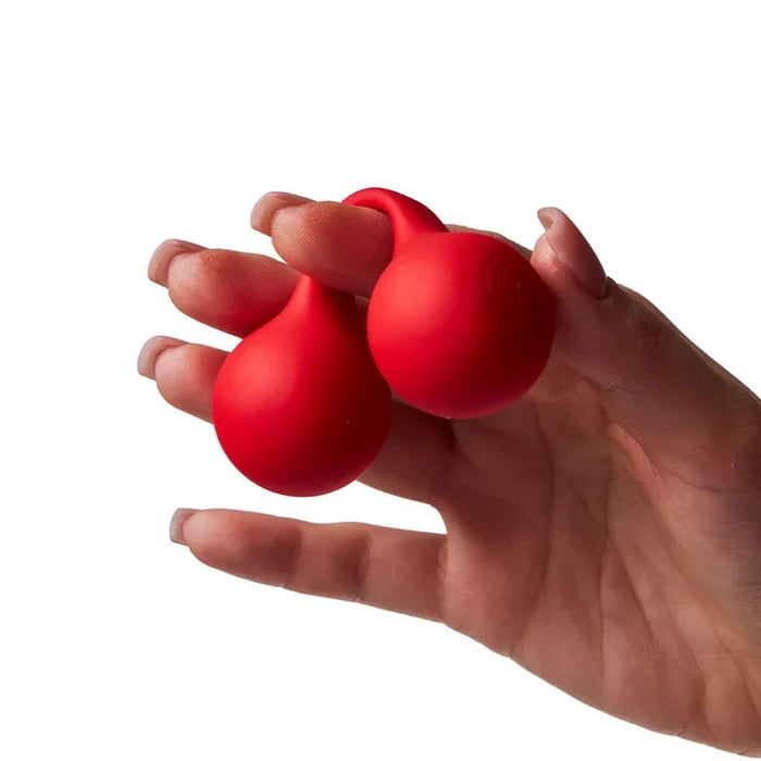 hand holding a set of red kegel balls