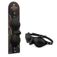 Temptasia Ardor Blindfold by Blush in black silicone with adjustable strap and molded eye covering design, shown alongside retail packaging and angled product view.