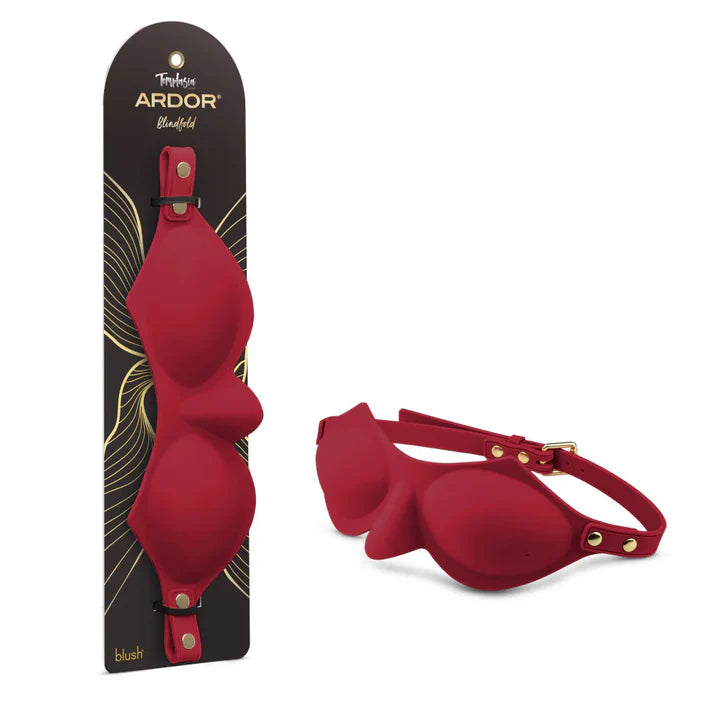 Temptasia Ardor Blindfold by Blush in red silicone with adjustable strap and molded eye covering design, shown alongside retail packaging and angled product view.