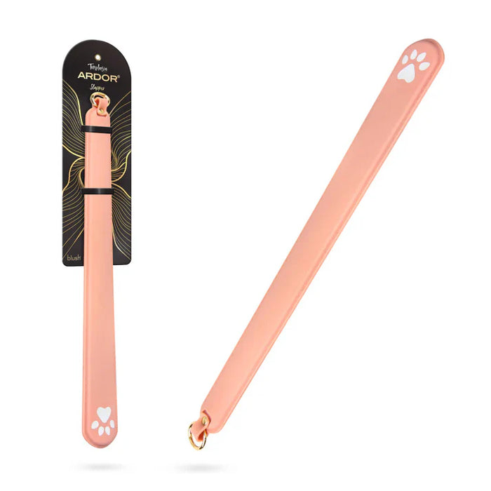 Temptasia Ardor Slapper by Blush silicone impact paddle in blush pink with paw print accents and retail packaging displayed beside the product.