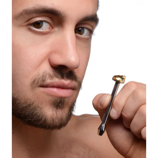 a white male holding a steel urethral rod with a golden skull top