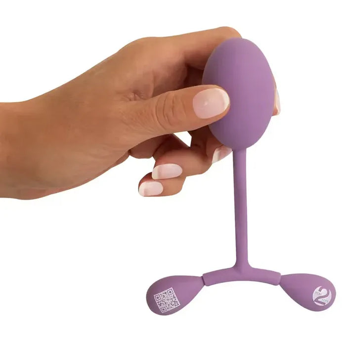 Purple vaginal trainer kegels held by a hand on a white background