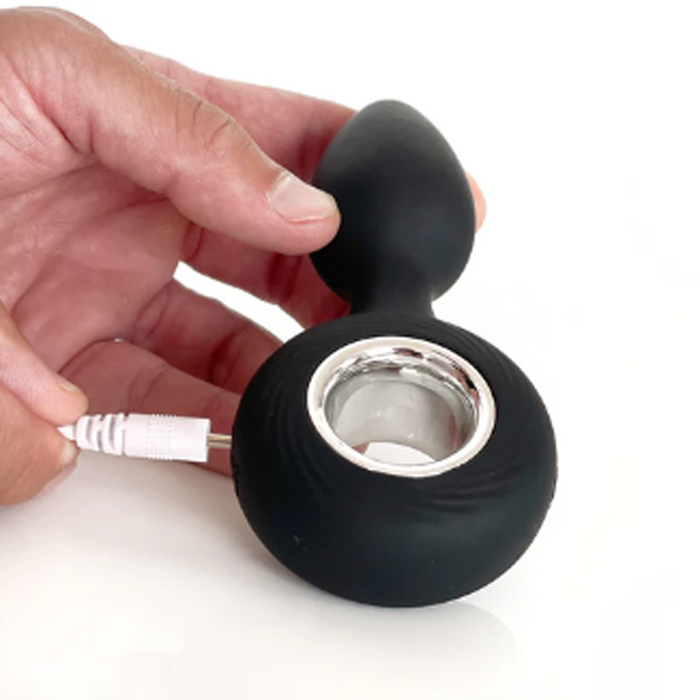 Black silicone product with a white cable being held by a hand on a white background