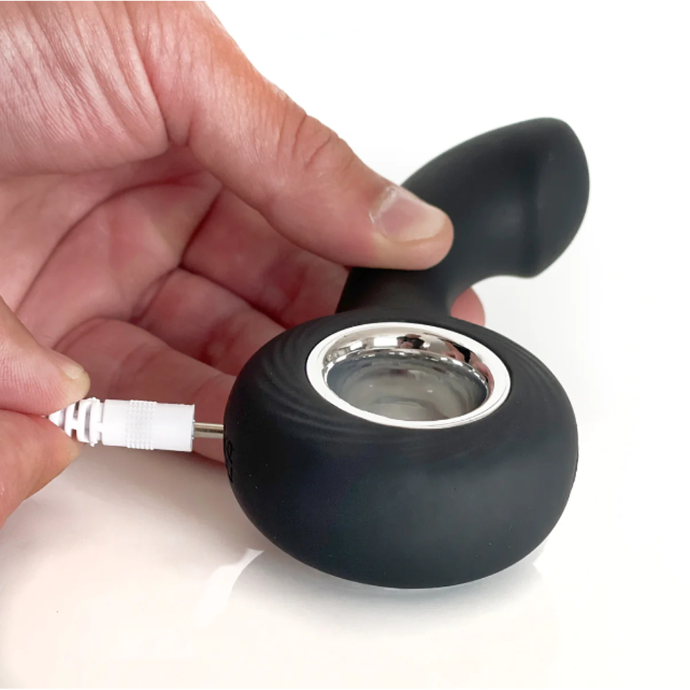 Black anal plug with metallic end held by a hand on a white background
