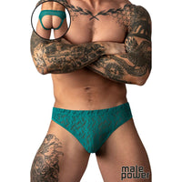 A tattooed male model wearing teal lace briefs against a white background, with a circular inset showing a close-up of the back of the underwear.