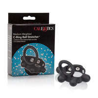 black silicone cock ring with 57g weighted ball stretcher next to cal exotics box