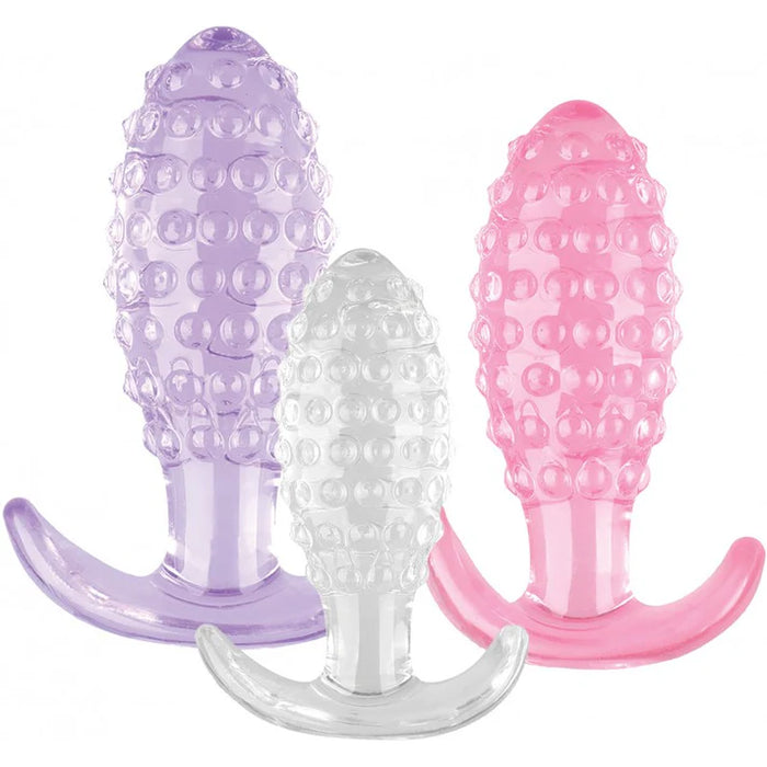 Three silicone butt plugs in purple, clear, and pink on a white background