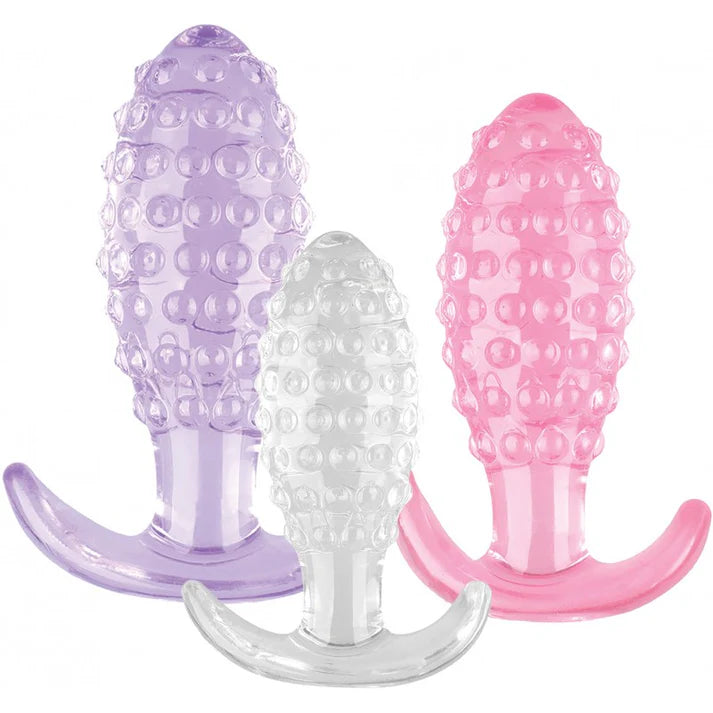 Three silicone butt plugs in purple, clear, and pink on a white background