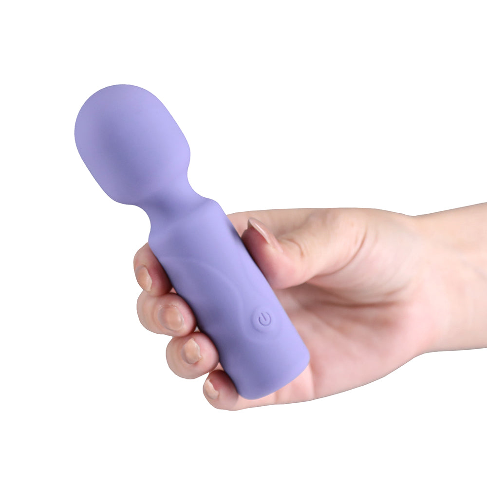 A hand holding a lavender purple silicone personal massager wand against a solid white background.