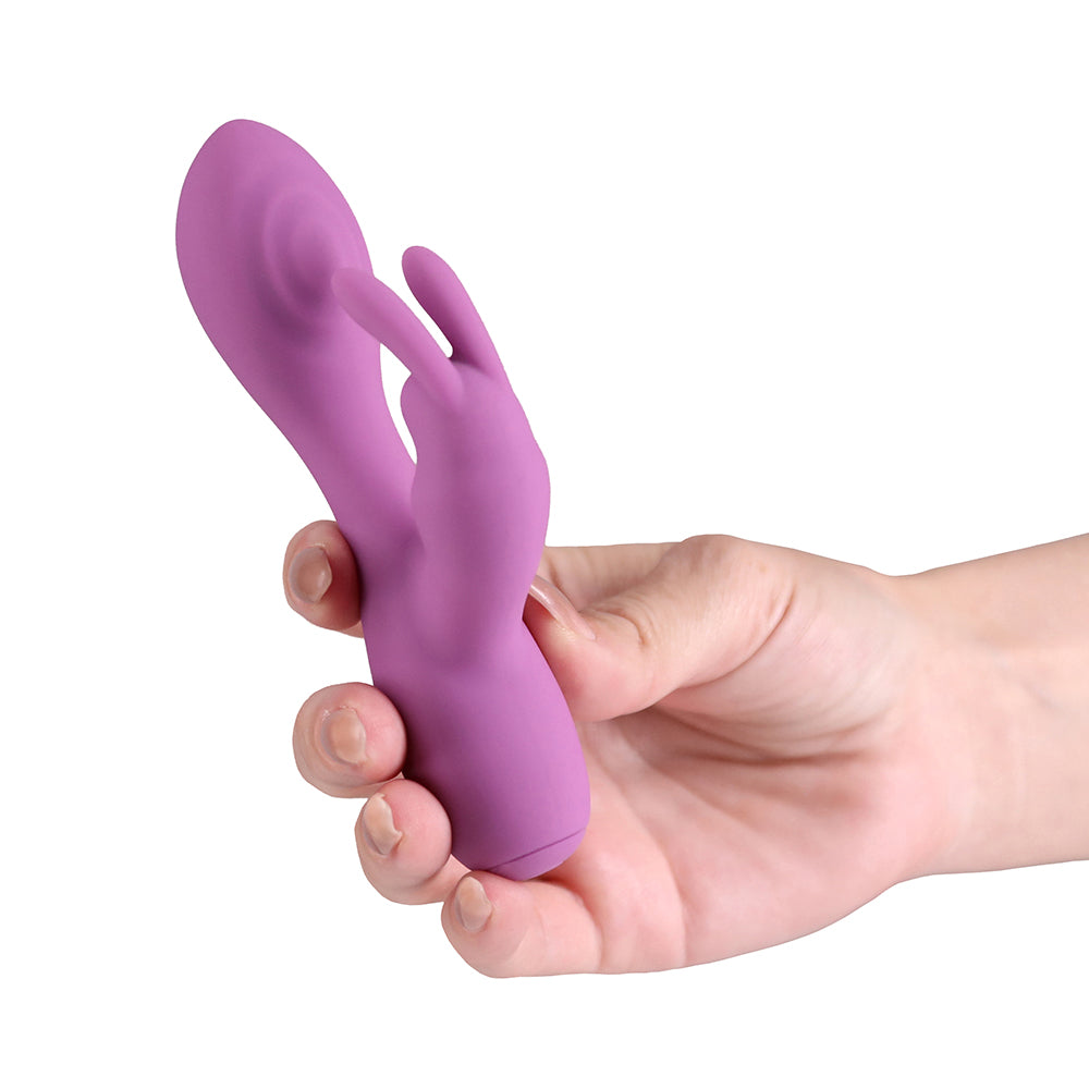 A purple silicone personal massager with a finger-like design, held in a person's hand against a plain white background.