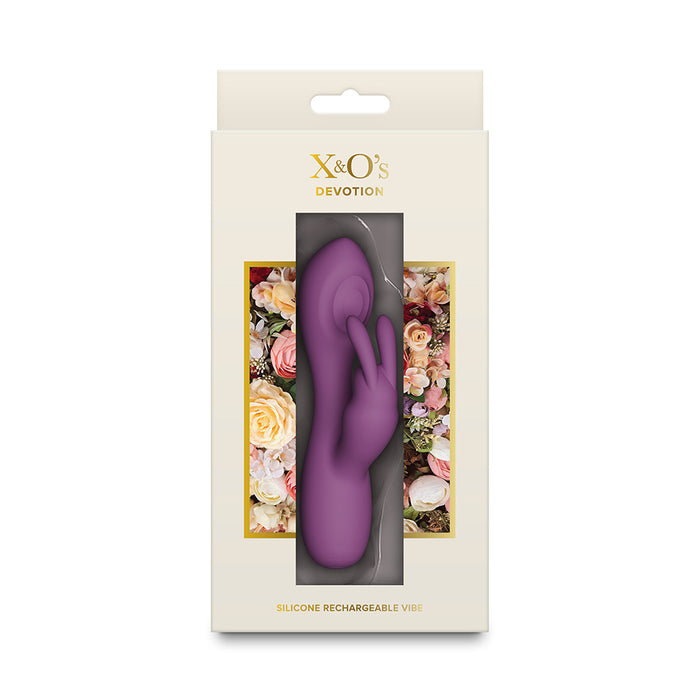 A purple silicone rechargeable vibrator with clitoral stimulator by X&O's Devotion, shown inside its cream-colored retail packaging with floral accents.