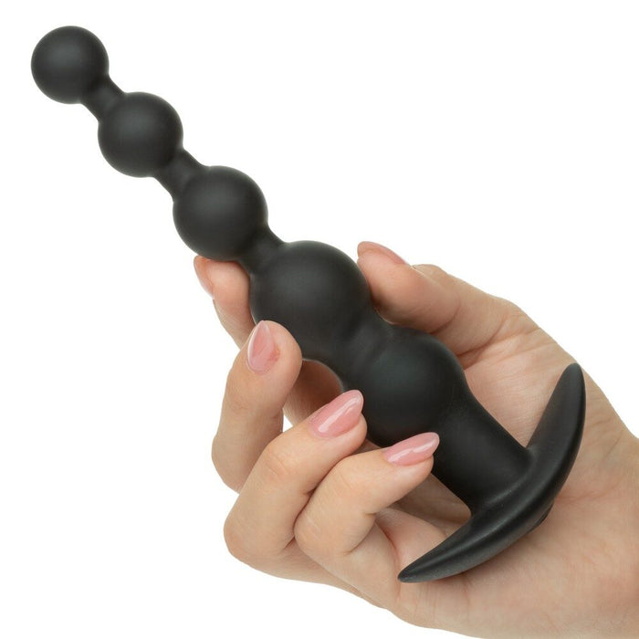 Black anal beads held in a hand with a white background