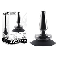 The product image shows a black metal anal plug with a rounded tip and a wide base that has a suction cup for hands-free use. The plug is displayed both in its packaging and separately.