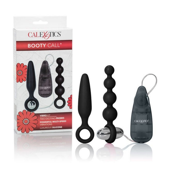 The image shows the product packaging for the Booty Call Vibro Vibrating Anal Plug Kit by Cal Exotics. The package contains three black silicone anal toys: a smooth probe, a set of graduated beads, and a vibrating bullet.