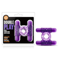 The image shows a purple vibrating cock ring with dual bullet vibrators. The product is displayed both in and out of its packaging, highlighting its features and giving a clear view of its design and color.
