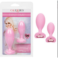 The product image shows a pink anal plug duo with heart-shaped crystal inlays at the base, packaged in a box with a 'First Time' branding.