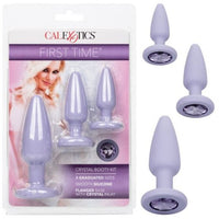 The image shows a set of three purple anal plugs with gem-adorned bases, packaged in a box with a 'First Time' branding and a model on the cover.