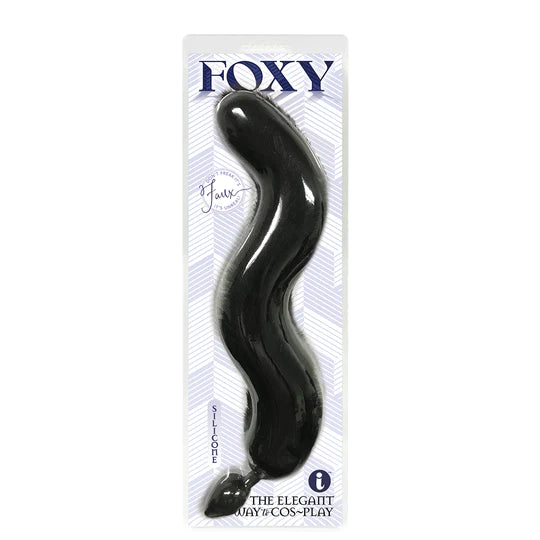 A black anal plug with a faux fur tail, packaged in a clear plastic case with the brand 'Foxy' displayed at the top.