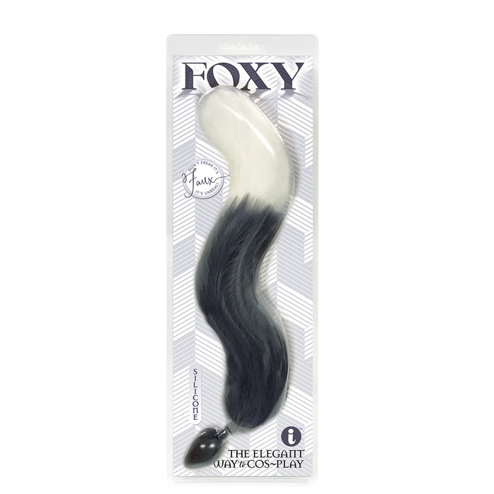 A grey anal plug with a faux fur tail, packaged in a clear plastic case with the brand 'Foxy' displayed at the top.