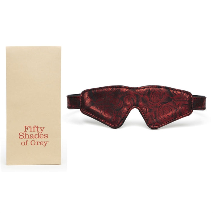 A red and black padded faux leather blindfold with a rose-print design, displayed next to its packaging that reads 'Fifty Shades of Grey'.