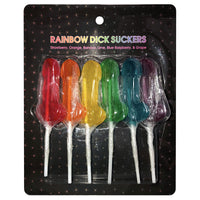 This image displays a pack of six Rainbow Dick Suckers, each lollipop crafted in the shape of a penis and presented in a variety of bright, multi-color hues. The lollipops are fruit-flavored, with flavors including strawberry, orange, banana, lime, blue raspberry, and grape, each clearly labeled on the packaging.