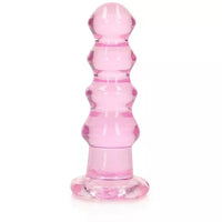 A pink, crystal-clear anal plug with a curved, bead-like design and a suction cup base.