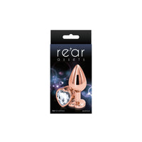 The product is an anal plug with a chrome-plated finish and a heart-shaped gem at the base. It is shown in its packaging, which is black with a space-themed background.