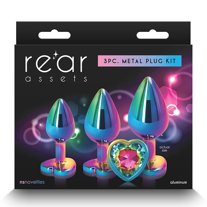 The image shows a 3-piece metal plug kit with a gradient of blue to green and a chrome-plated finish. The plugs are displayed in different sizes, with the smallest having a heart-shaped base, and the set is packaged in a black box with the brand 'Rear Assets' prominently shown.