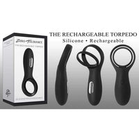 The image shows the Torpedo Vibrating Cock Ring by Zero Tolerance, including the product packaging, the black silicone ring, and the USB rechargeable base. The packaging highlights the features such as being rechargeable and made of silicone.