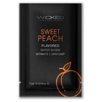 The image displays a packet of Wicked Sensual Care® Sweet Peach Flavored Lubricant. The packaging is sleek and modern, featuring a dark background with the product name "SWEET PEACH" in bold, white letters.