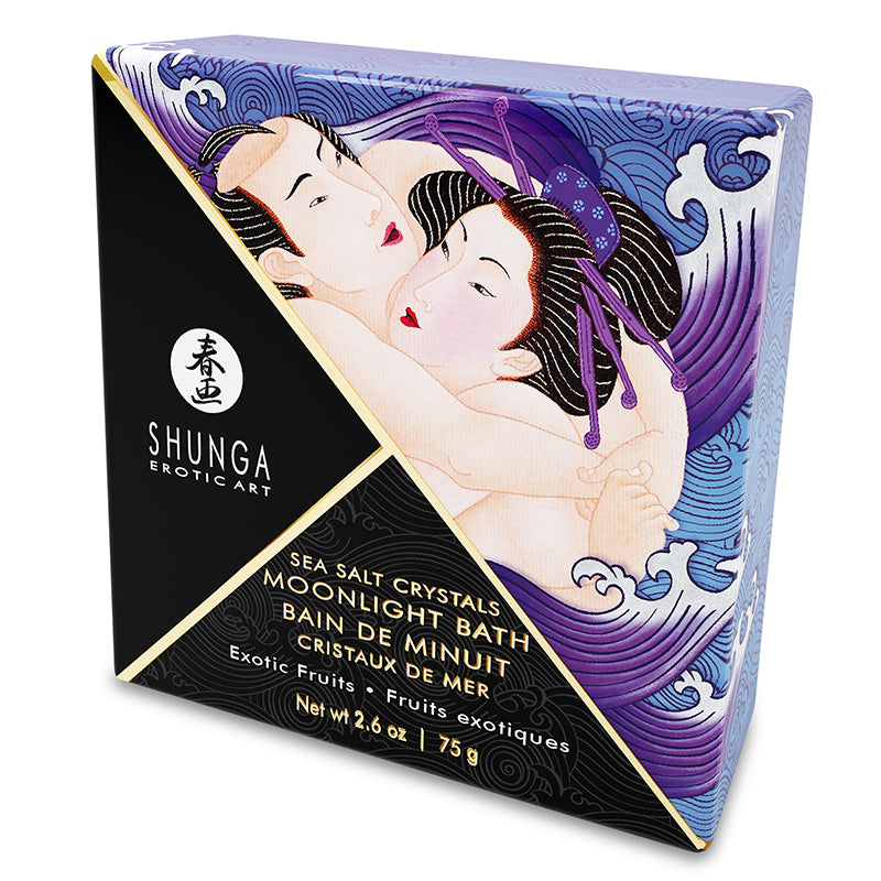 A square container of Shunga Dead Sea salt bath crystals with exotic fruit scent, accompanied by an illustration of a woman and various fruits like grapes and apples. A sea shell scoop is also shown beside the container.