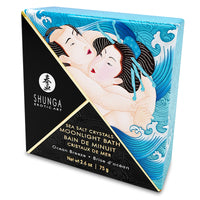 A square container of Foaming Scented Dead Sea Salt with a graphic of a woman in a bathtub on the label, alongside a blue starfish and a scoop of blue salt crystals.